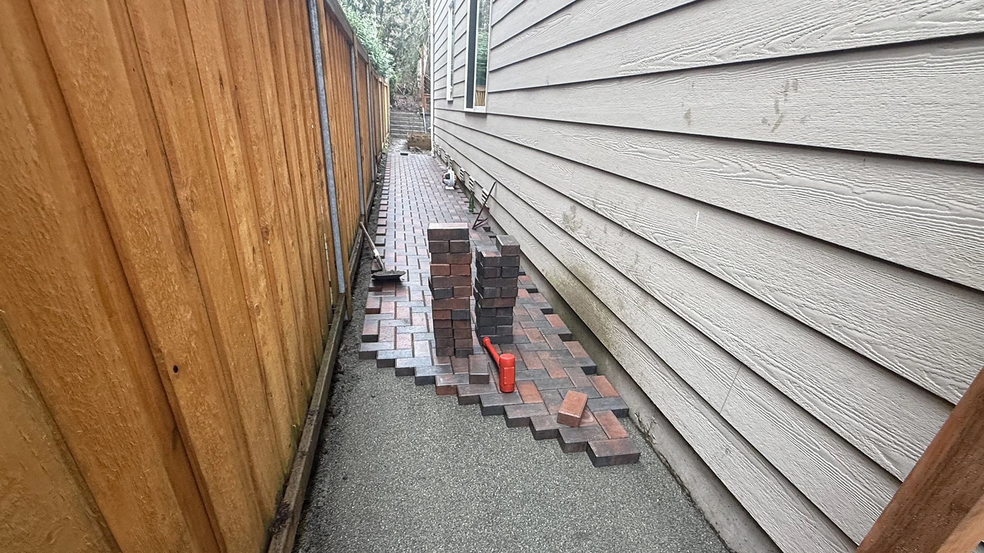 Laying herringbone pavers on a compacted gravel base in a Sammamish side yard