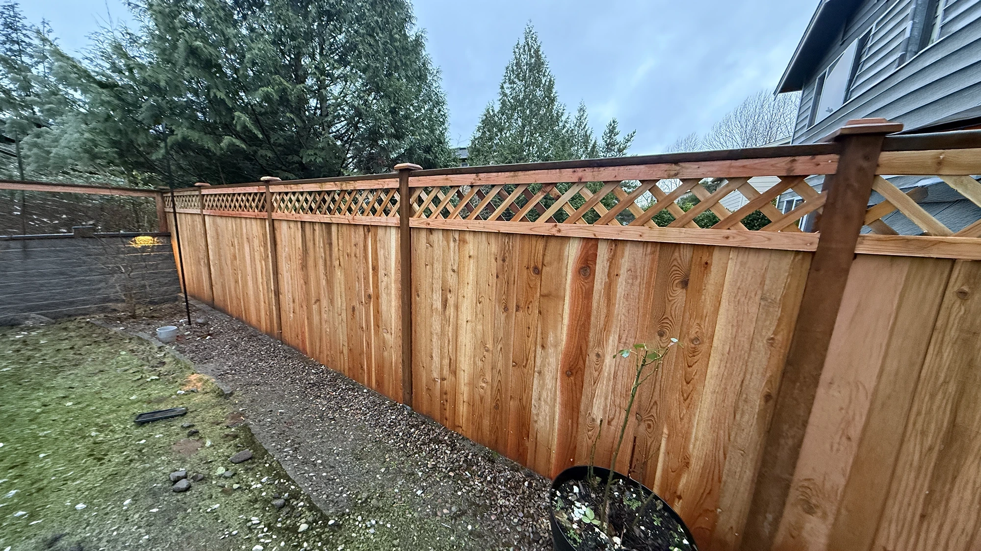 Cedar lattice fence meeting a lit block retaining wall in a Sammamish backyard