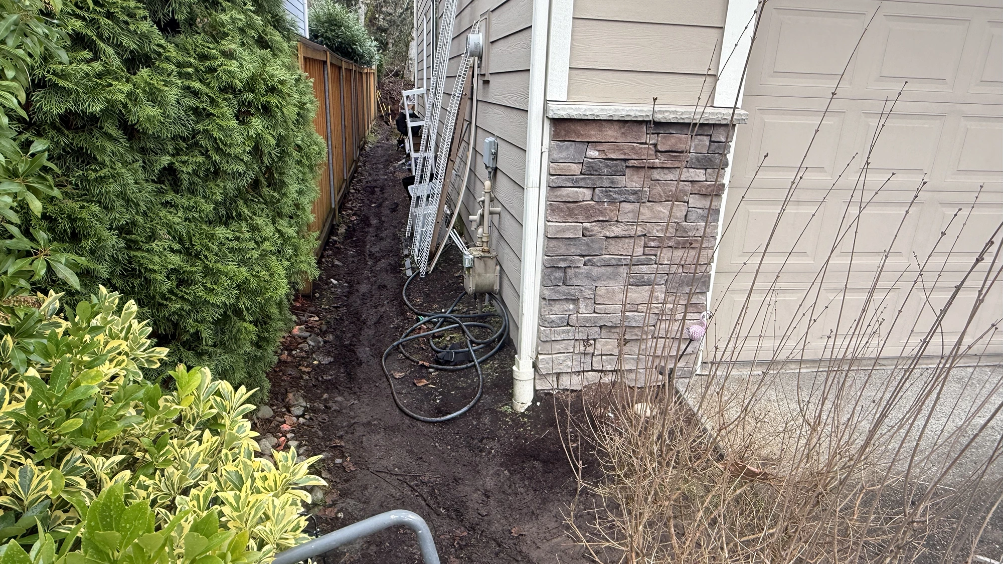 Narrow dirt side yard beside the garage before the paver walkway in Sammamish, WA