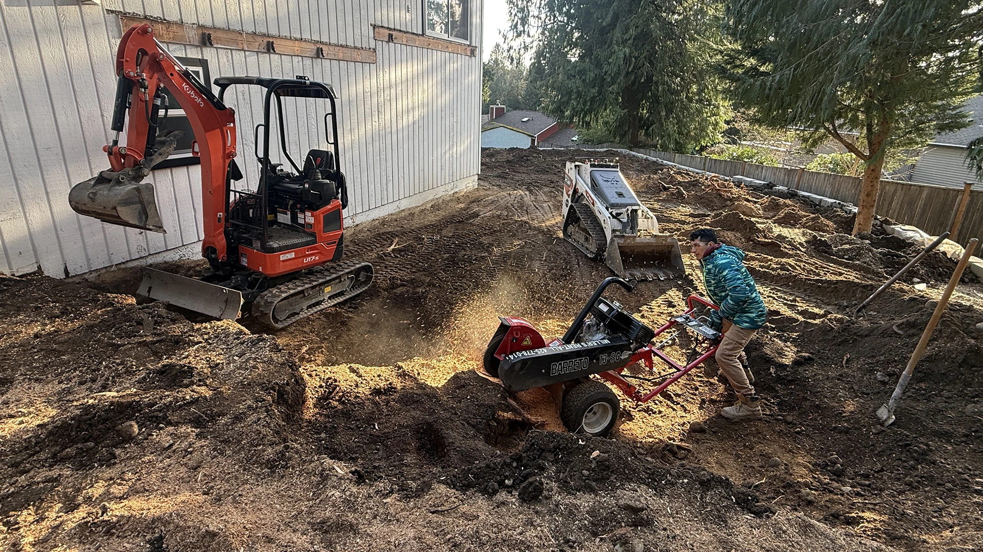 Mini excavator and stump grinder clearing the backyard in Bothell, WA