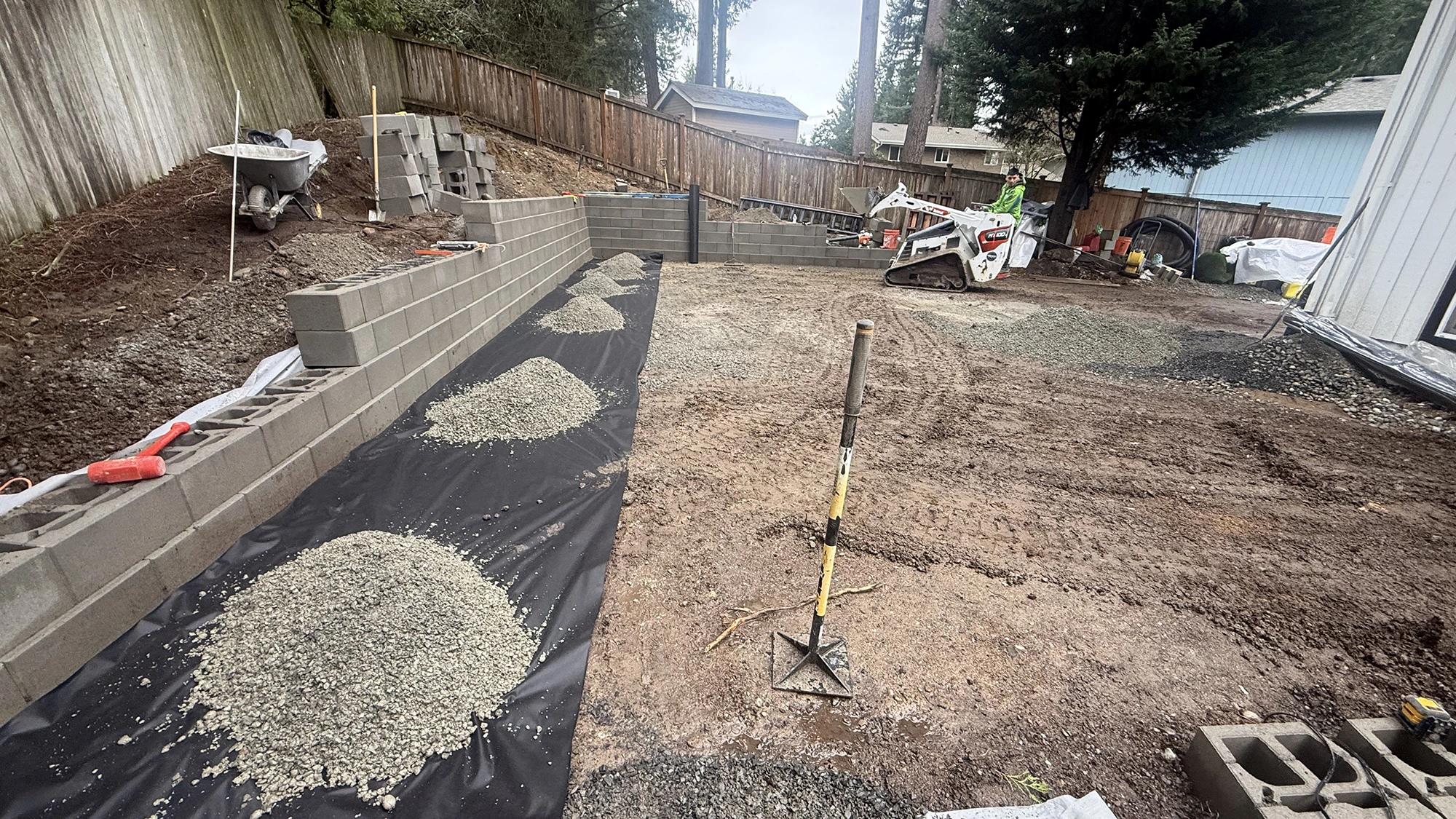 Drain rock, filter fabric and block wall base behind the new patio in Bothell