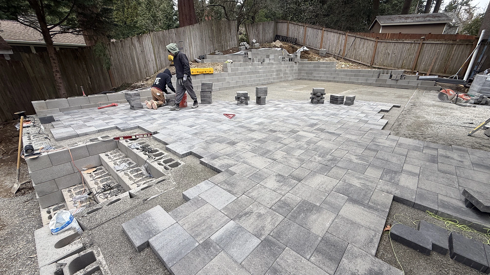 Crew laying gray blend pavers on a screeded sand bed in Bothell, WA
