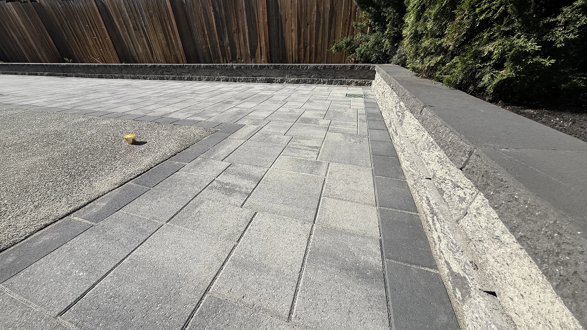 Finished backyard paver patio, retaining wall and charcoal border around the aggregate pad in Mill Creek