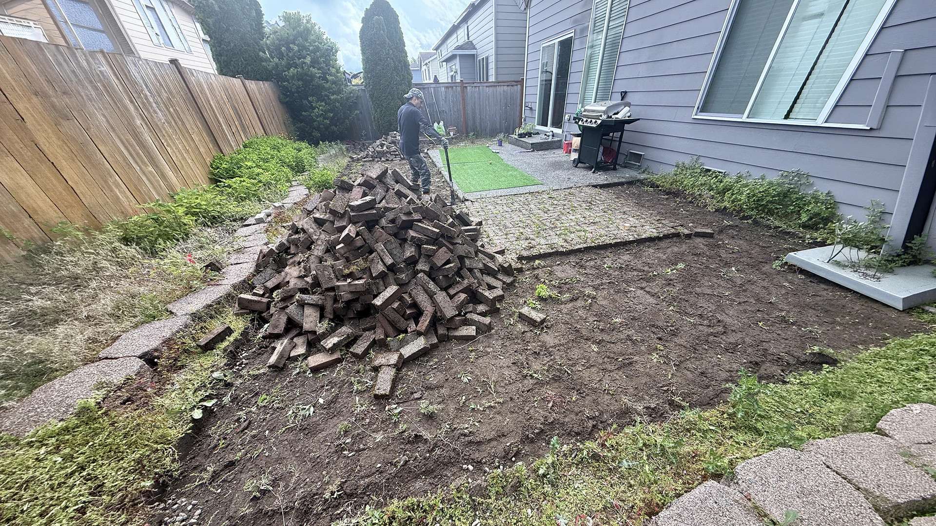 Old brick patio removed and stacked in the backyard before the new paver patio in Mill Creek
