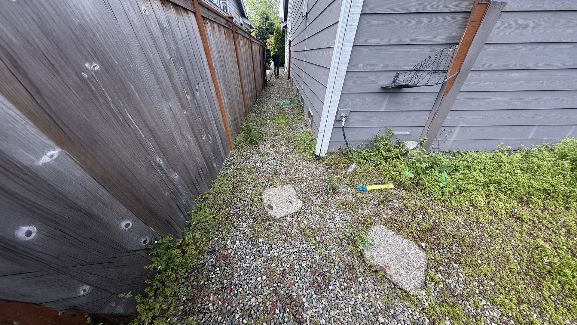 Weedy gravel side yard with loose stepping stones before the paver walkway in Mill Creek, WA