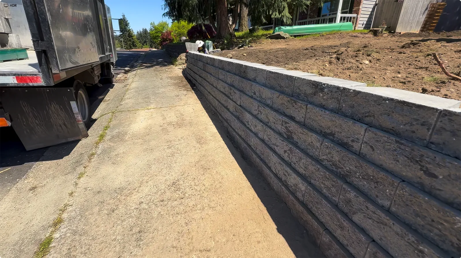 New concrete block retaining wall rising along the sidewalk in Federal Way, WA