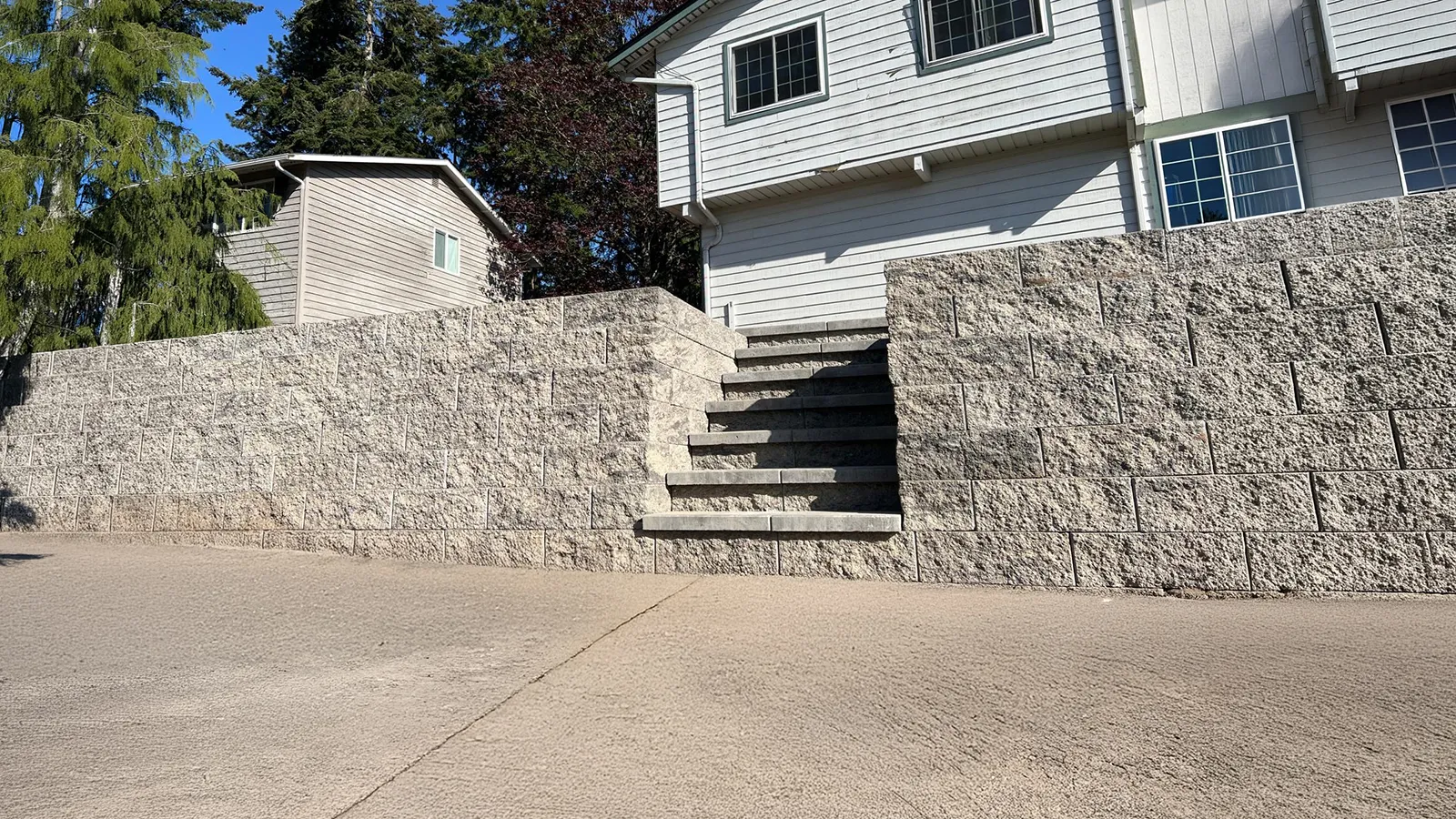 Tall concrete block retaining wall with built-in stairs beside the house in Federal Way, WA