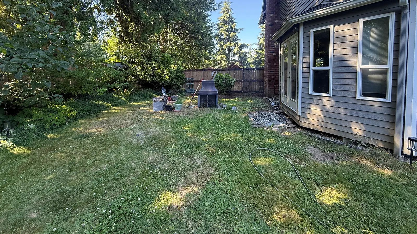 Backyard lawn beside the house before paver patio installation in Duvall, WA