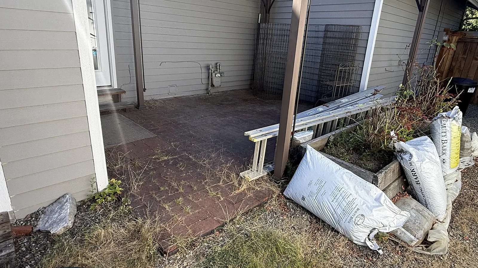 Old brick paver patio with weeds before the backyard renovation in Duvall, WA