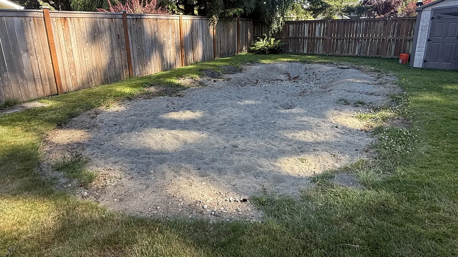 Uneven sand and gravel area in the backyard before renovation in Duvall, WA
