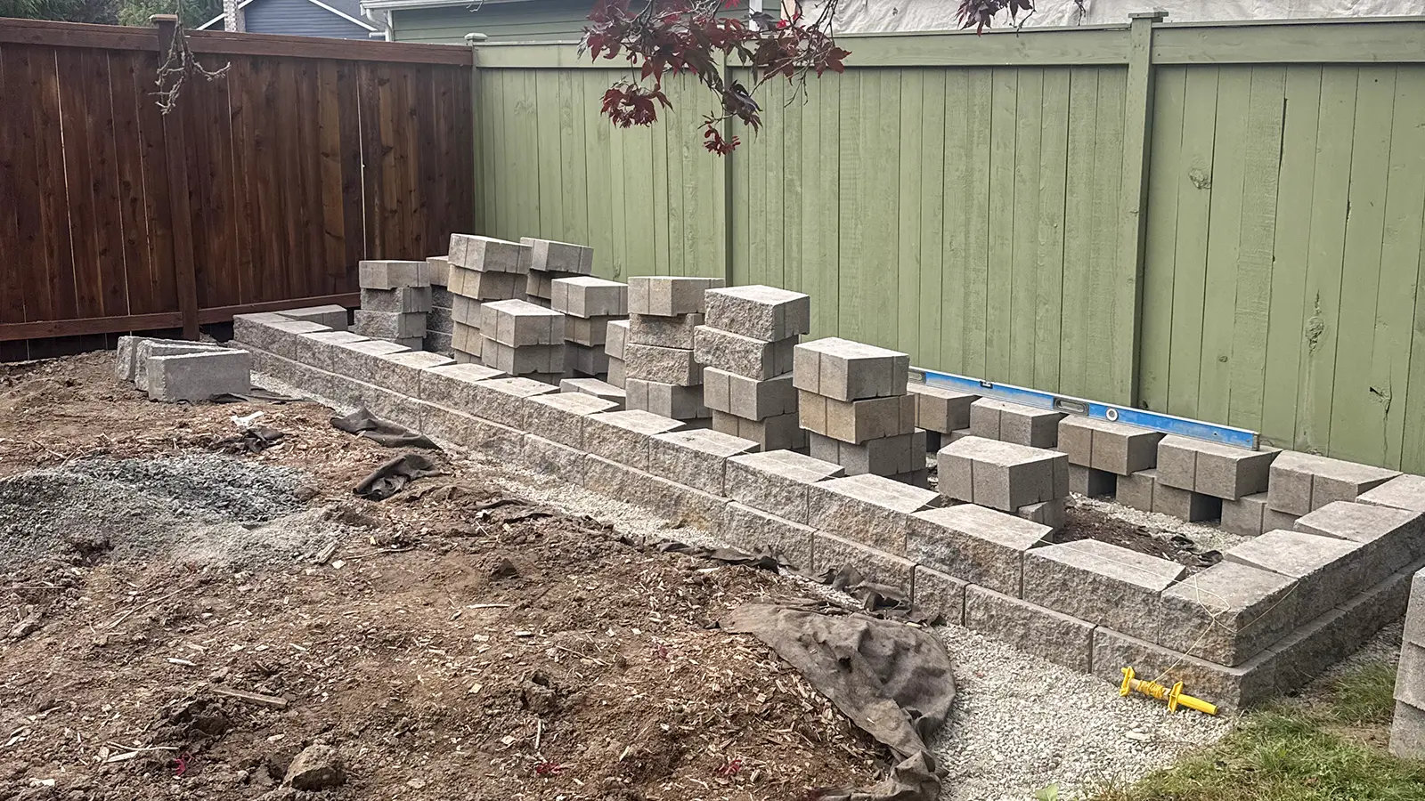 Retaining wall blocks staged along the fence for a backyard patio in Duvall, WA