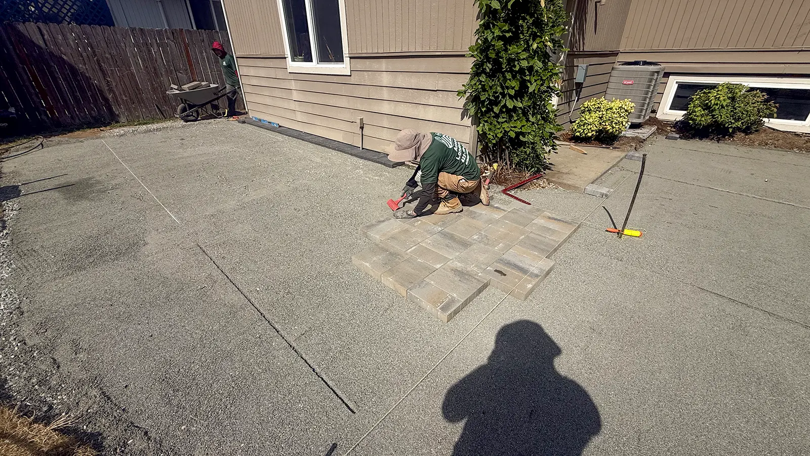 Crew setting the first tan-gray pavers on a compacted gravel base in Bothell, WA
