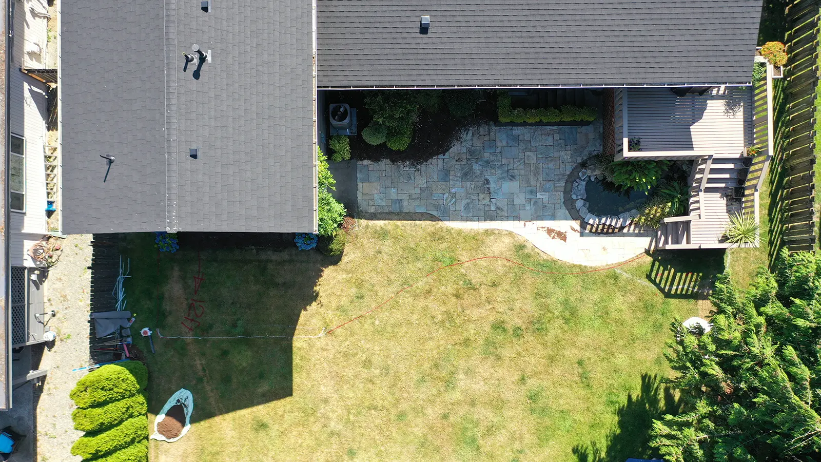 Aerial view of a Bothell, WA backyard with lawn and an old flagstone patio before paver installation