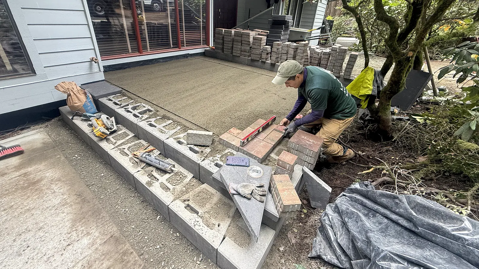 Installer leveling red blend pavers on a screeded sand bed in Bothell, WA