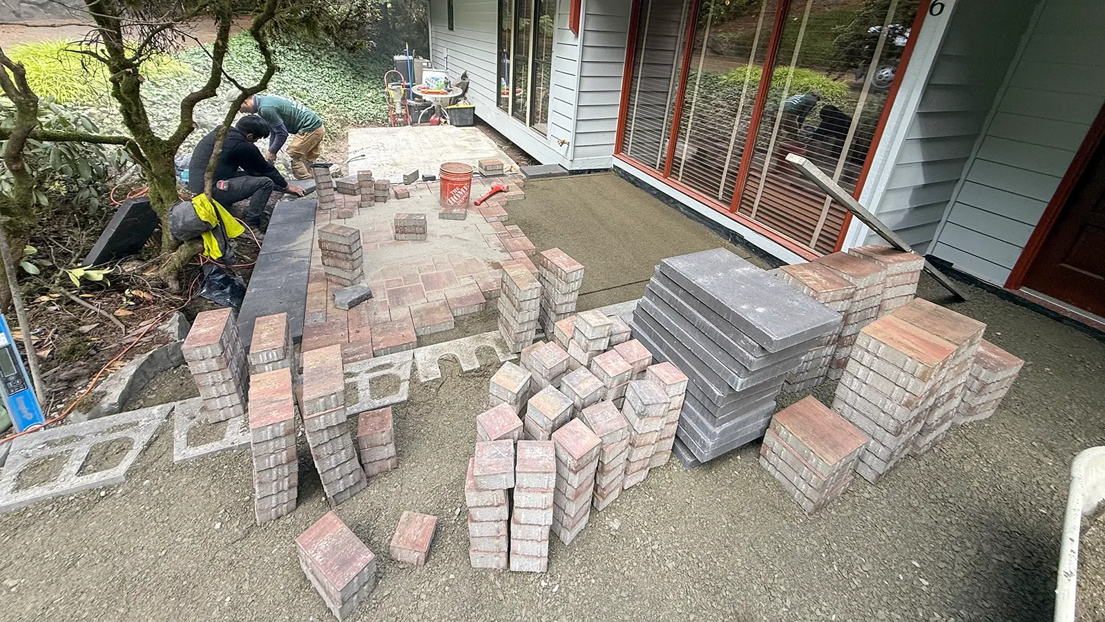 Red blend pavers and charcoal step caps staged during patio construction in Bothell, WA