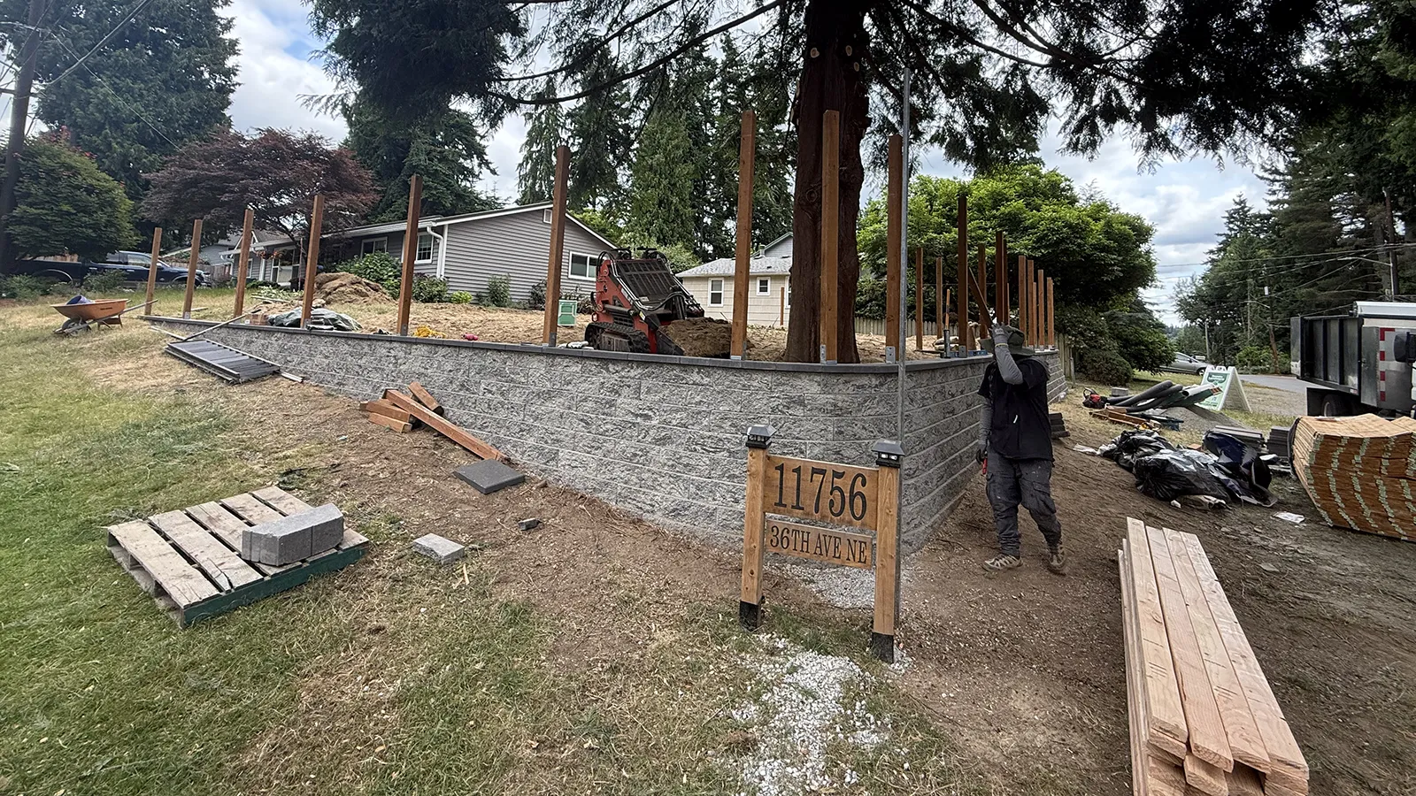 Retaining wall complete with cedar fence posts being set on top in Seattle, WA
