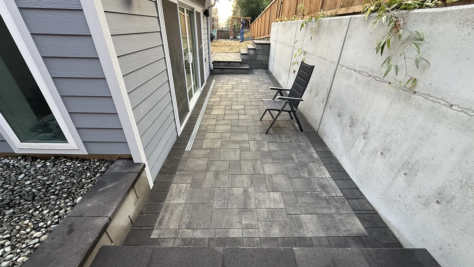 Completed side yard paver patio with charcoal border and steps in Bothell, WA