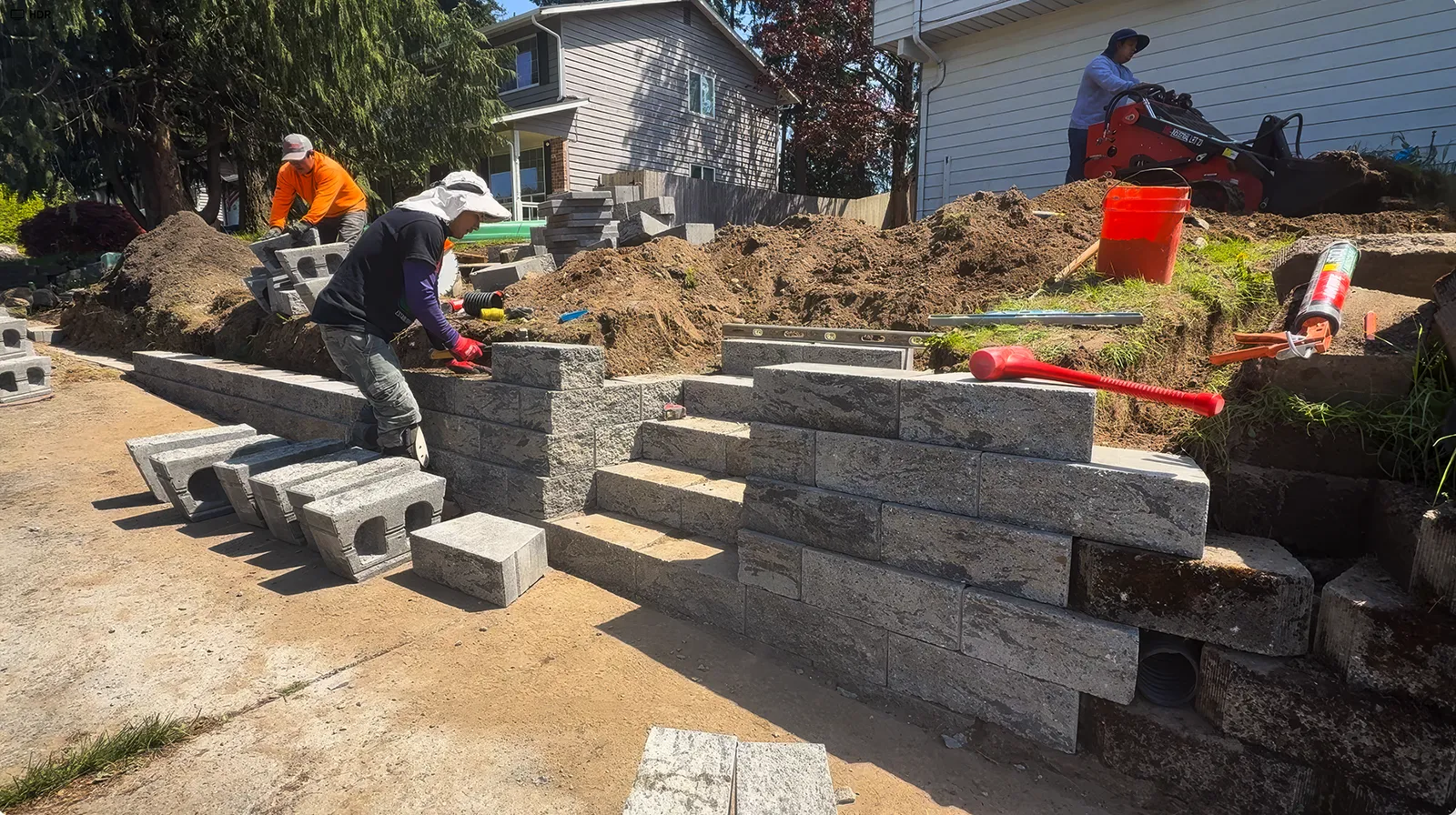 Crew building the concrete block retaining wall and stairs with drain pipe behind it in Federal Way