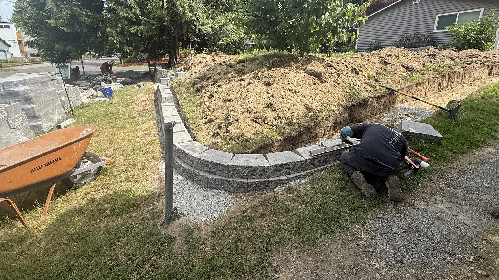Installer leveling a curved concrete block retaining wall in Seattle, WA