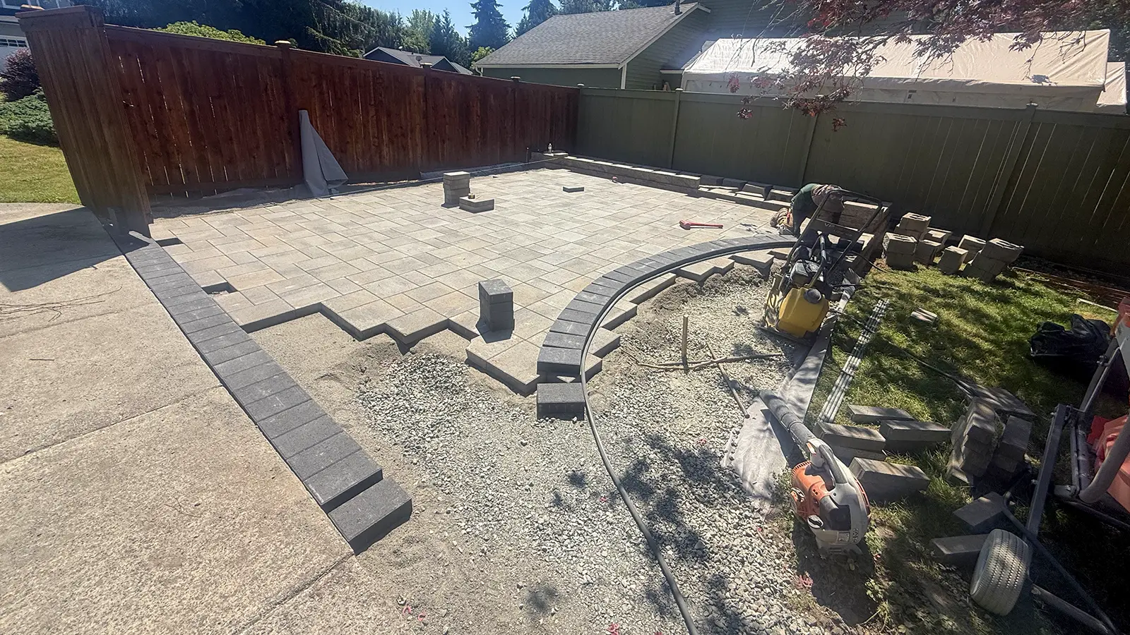 Paver patio installation with curved charcoal border in Duvall, WA