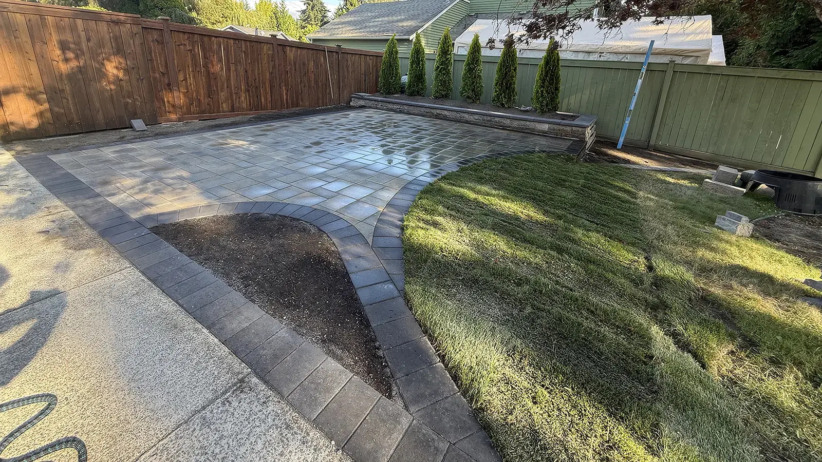 Finished curved paver patio with new sod and arborvitae in Duvall, WA by Acosta Landstone