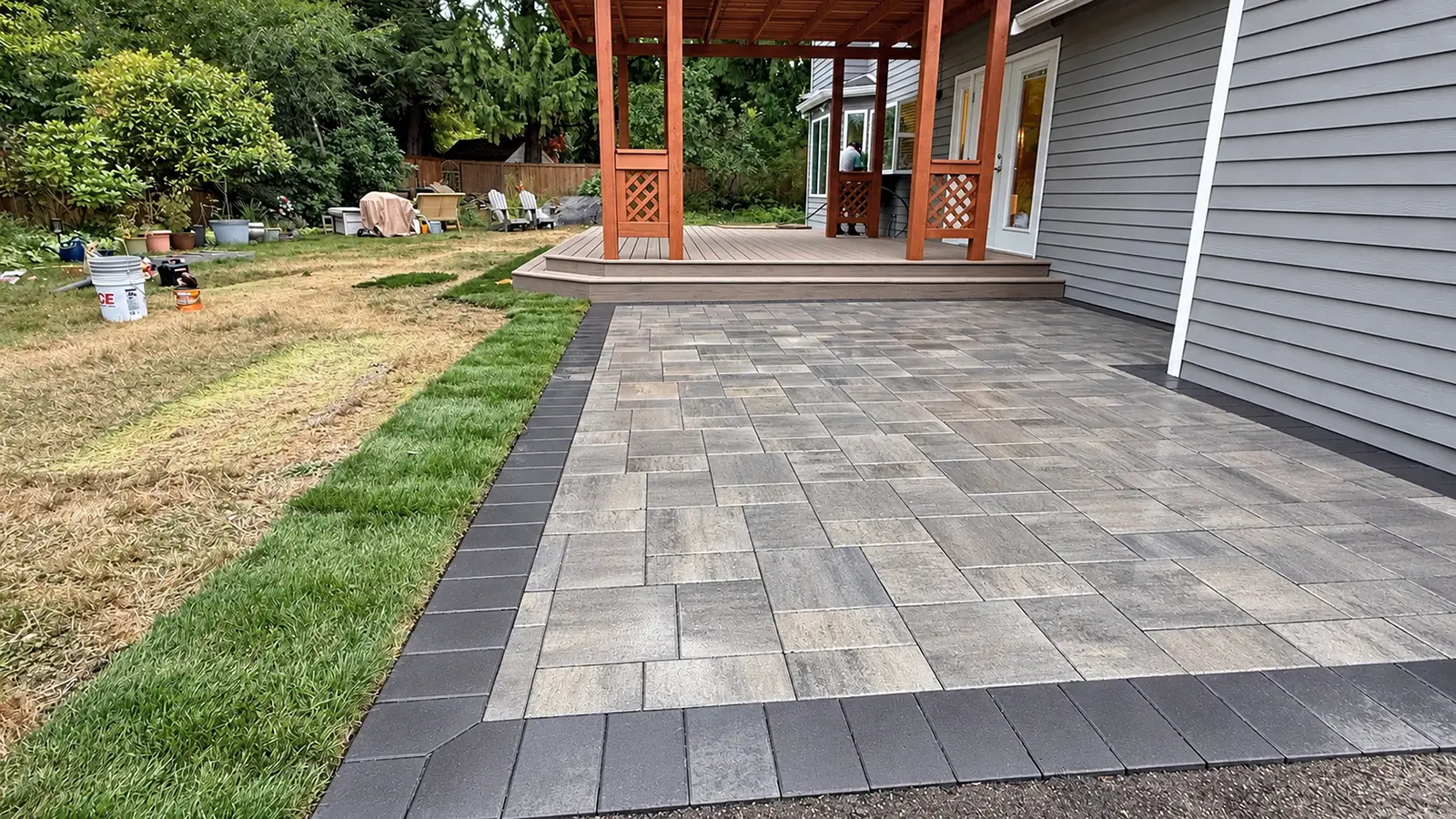 Finished gray paver patio with charcoal border, new sod and composite deck in Duvall, WA