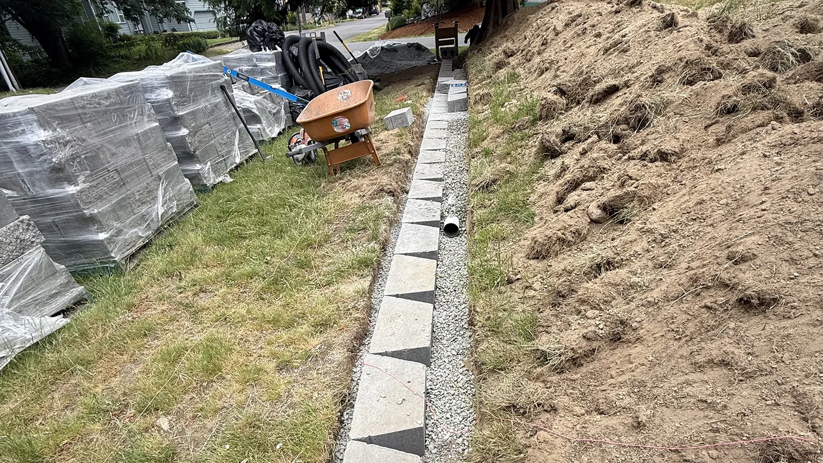 Base course blocks and drain pipe in drain rock behind a retaining wall in Seattle, WA