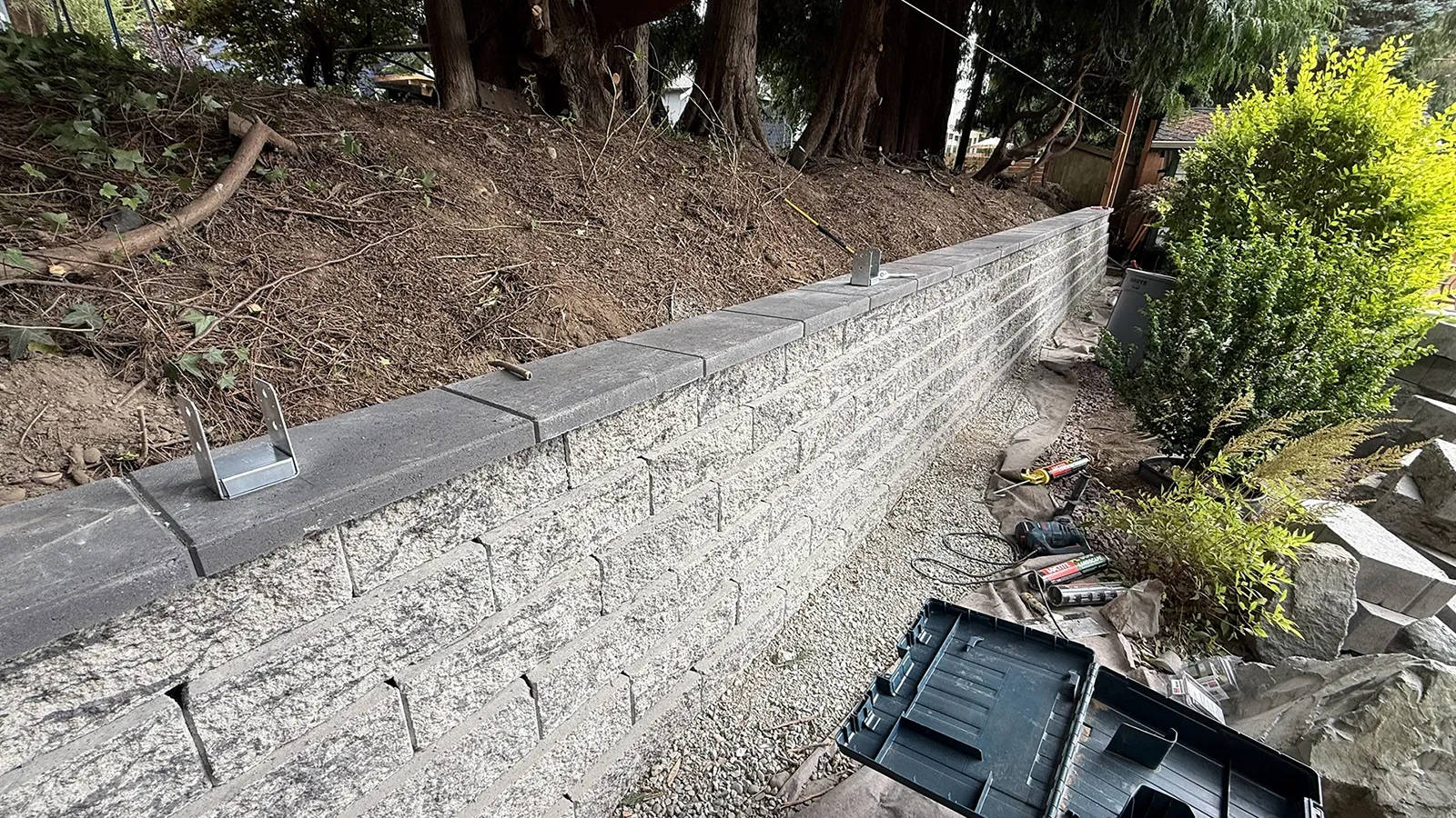 Retaining wall cap with post brackets anchored for a wall-top fence in Seattle, WA
