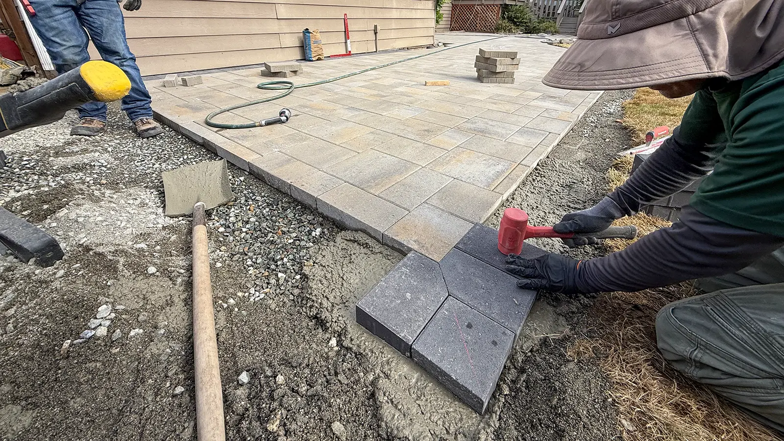Leveling charcoal border pavers set in a concrete edge restraint in Bothell, WA