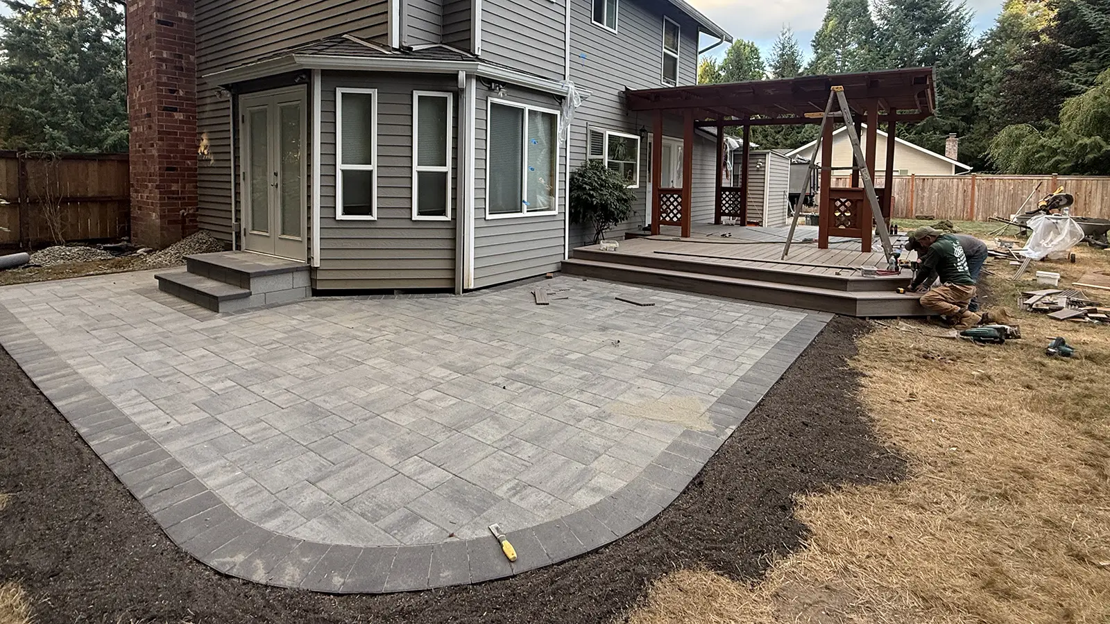Large paver patio with curved charcoal border and paver steps in Duvall, WA