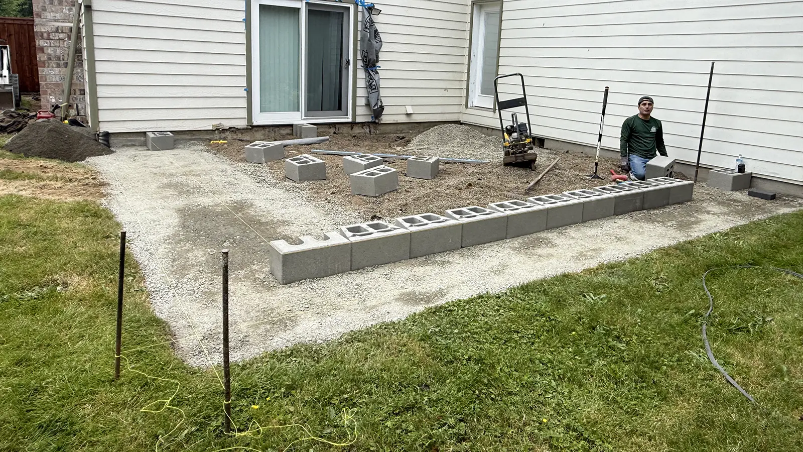 Compacted gravel base and block layout for a raised paver patio in Duvall, WA