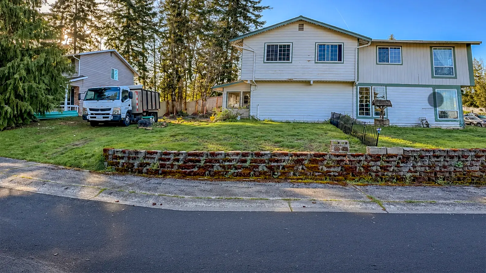 Old moss-covered block retaining wall and overgrown front yard before the renovation in Federal Way, WA