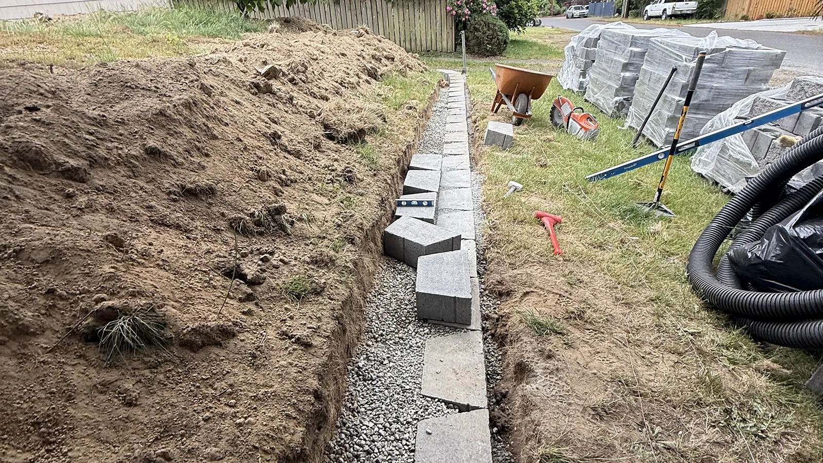 First course of concrete retaining wall blocks set on a leveled gravel base in Seattle
