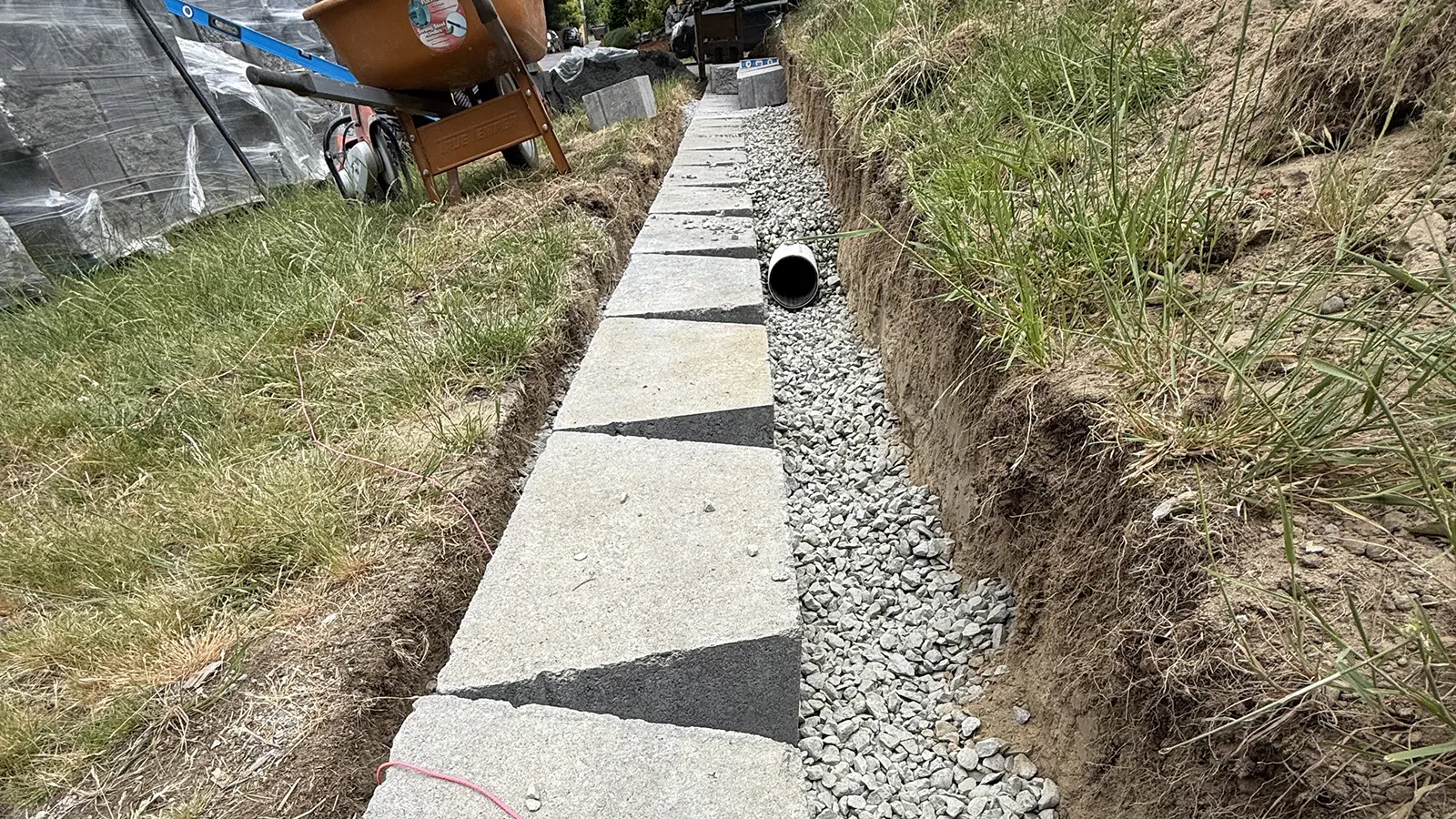 Perforated drain pipe and clean drain rock behind the retaining wall base in Seattle