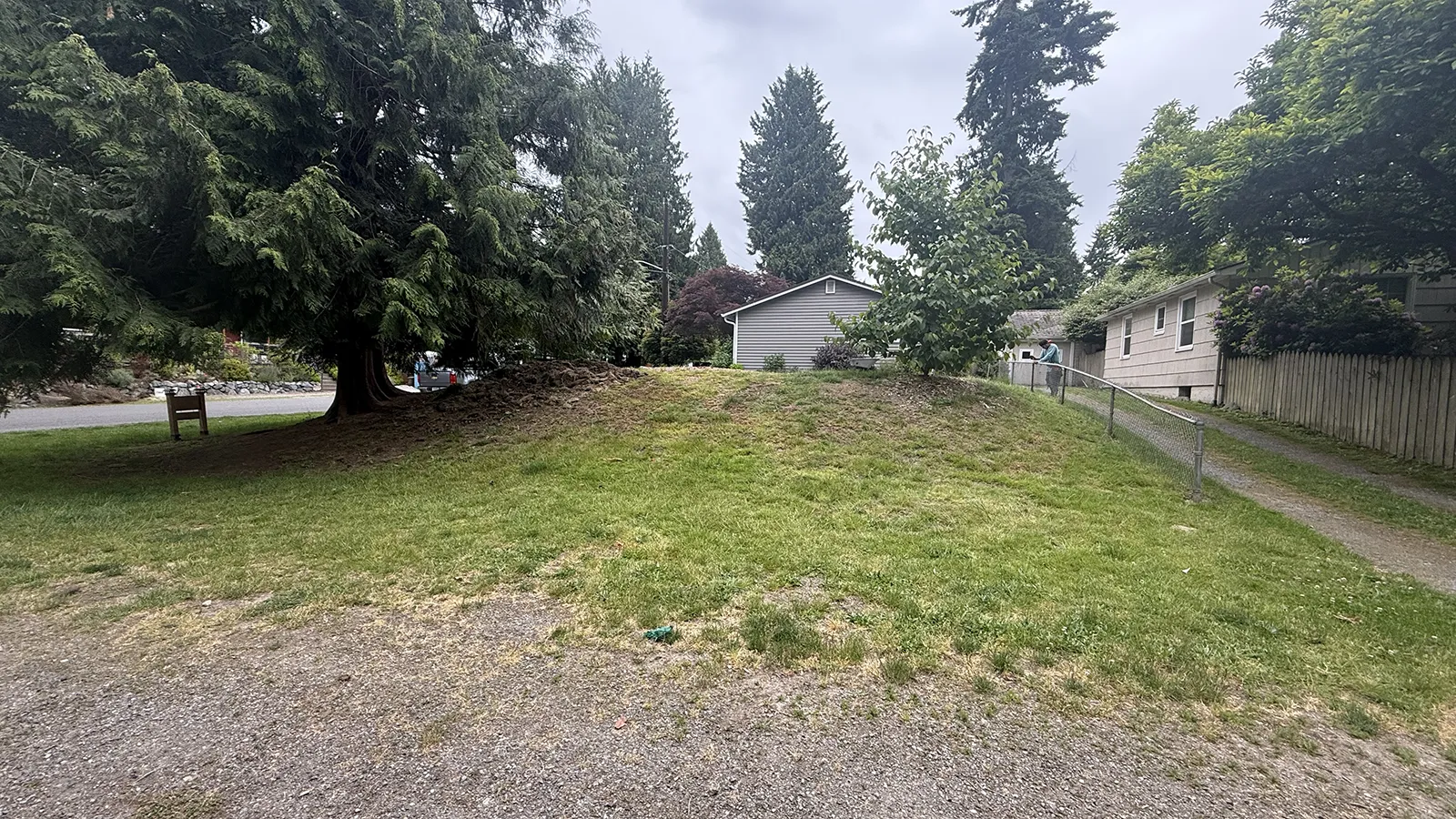 Grass mound and sloped corner lot before the retaining wall project in Seattle, WA