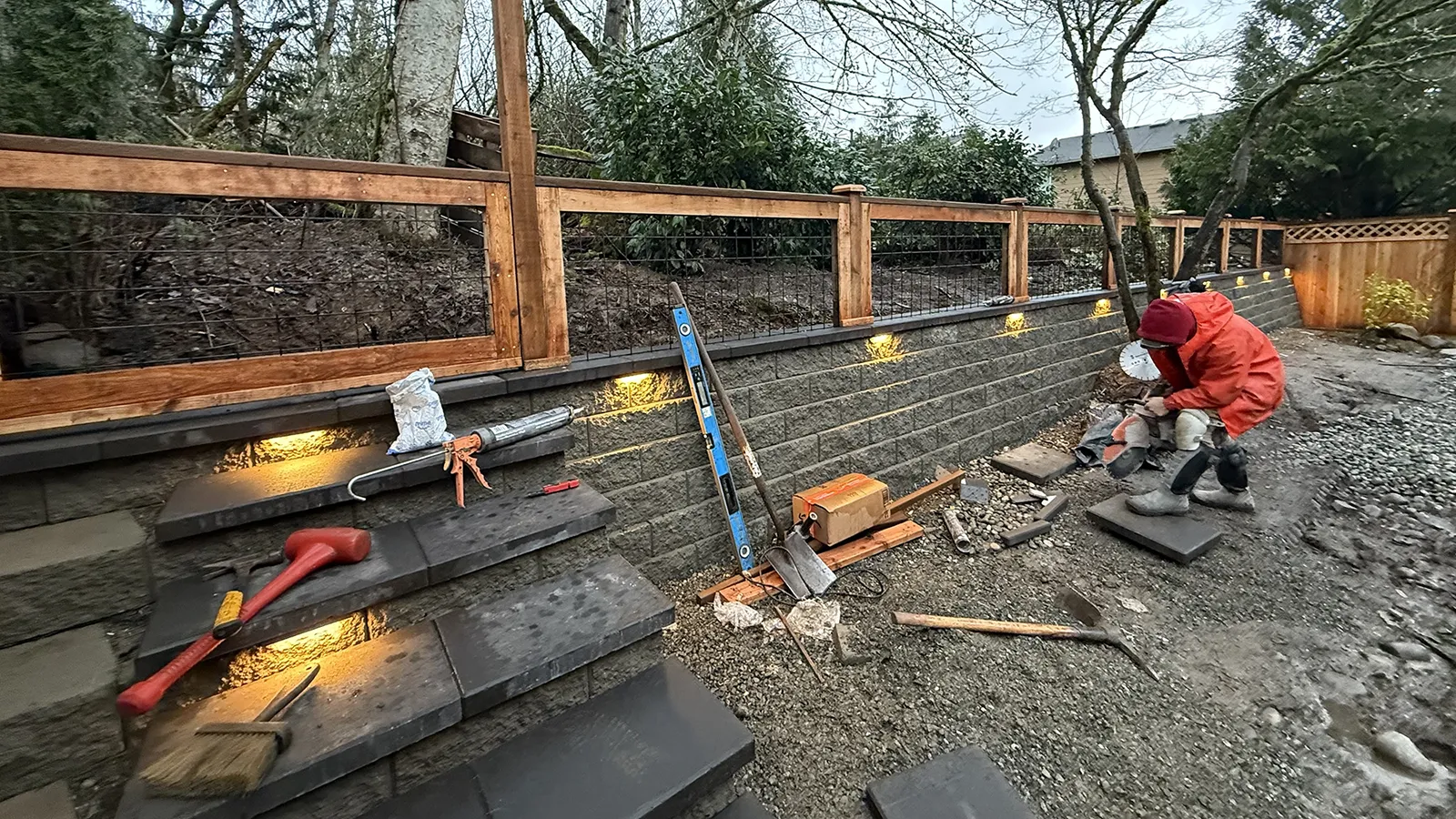Block steps with built-in lights and a wood and wire fence on a retaining wall in Sammamish, WA