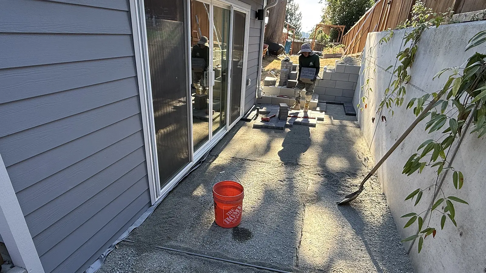 Compacted gravel base and first pavers by the sliding doors in a Bothell, WA side yard